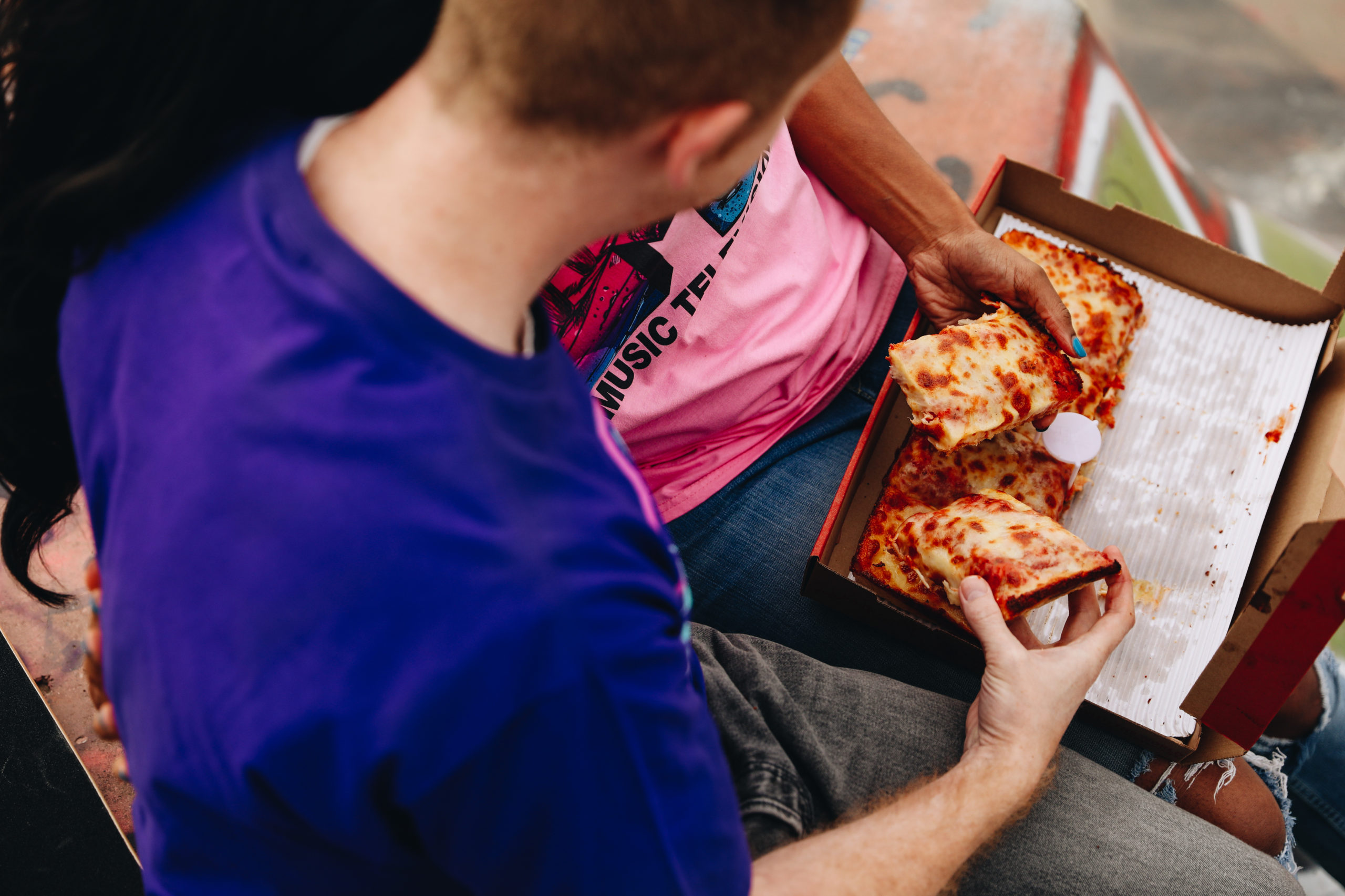 Couple at a skatepark in Detroit, Michigan enjoying pizza.
